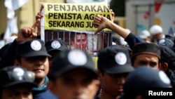 A protester holds a banner outside a court during the first day of the blasphemy trial of Jakarta's Governor Basuki Tjahaja Purnama, also known as Ahok, in Jakarta, Indonesia December 13, 2016.