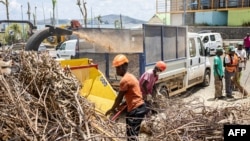 Workers clean a street in the city of Mamoudzou on the French Indian Ocean territory of Mayotte, which was devastated by a cyclone, on Dec. 29, 2024.