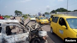 FILE - A taxi passenger looks at a burned police car, after two groups of Muslims clashed outside Martyrs Stadium in Kinshasa, Democratic Republic of the Congo May, 13, 2021. 