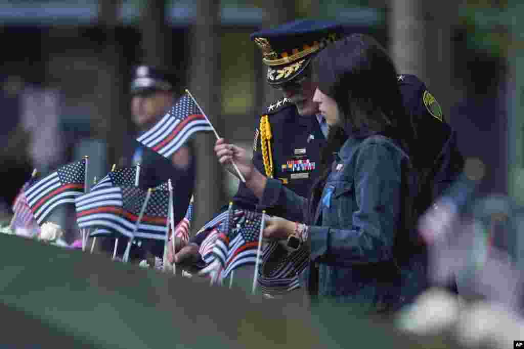 Sam Pulia, left, police chief in Willow Springs, Illinois, places flags on the bronze parapets at the 9/11 Memorial on the 23rd anniversary of the terror attacks, in New York, Sept. 11, 2024.