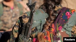 FILE - A Syrian Democratic Forces (SDF) female fighter's braid is pictured while she is carrying her weapon in Tal Samin village, north of Raqqa city, Syria, Nov. 19, 2016. The Syrian government has created an all-female military unit in a predominantly Kurdish city in northeastern Syria.