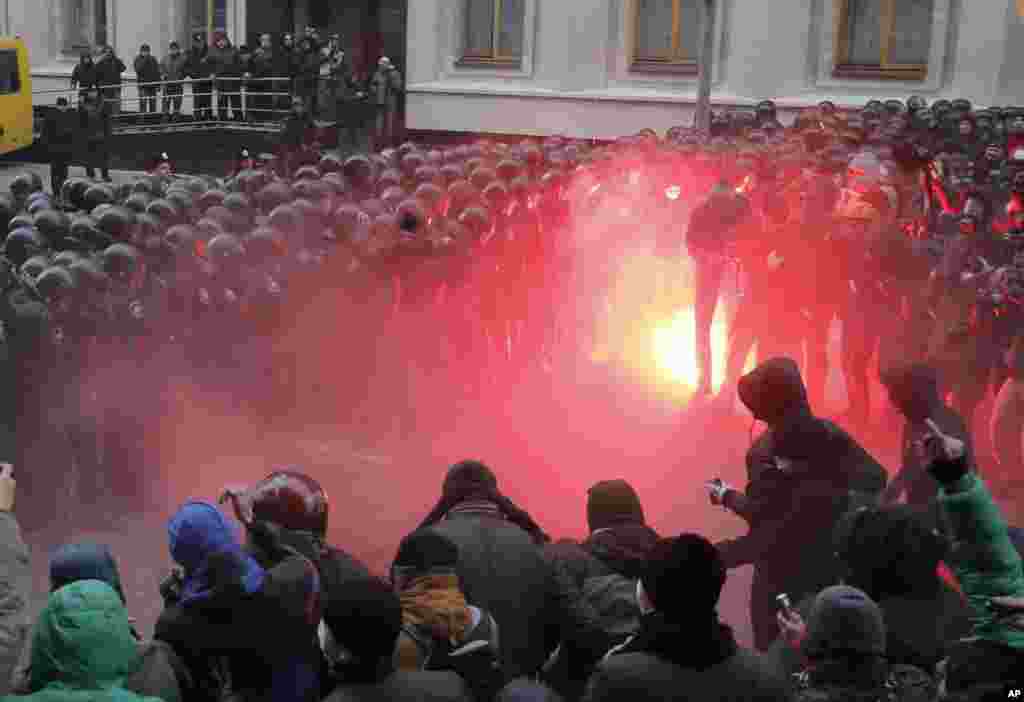 Protesters throw stones as they clash with police at the presidential office in Kyiv, Ukraine. As many as 100,000 demonstrators chased away police to rally in the center of the capital, defying a ban on protests in Independence Square, in the biggest show of anger over the president&#39;s refusal to sign an agreement with the European Union.