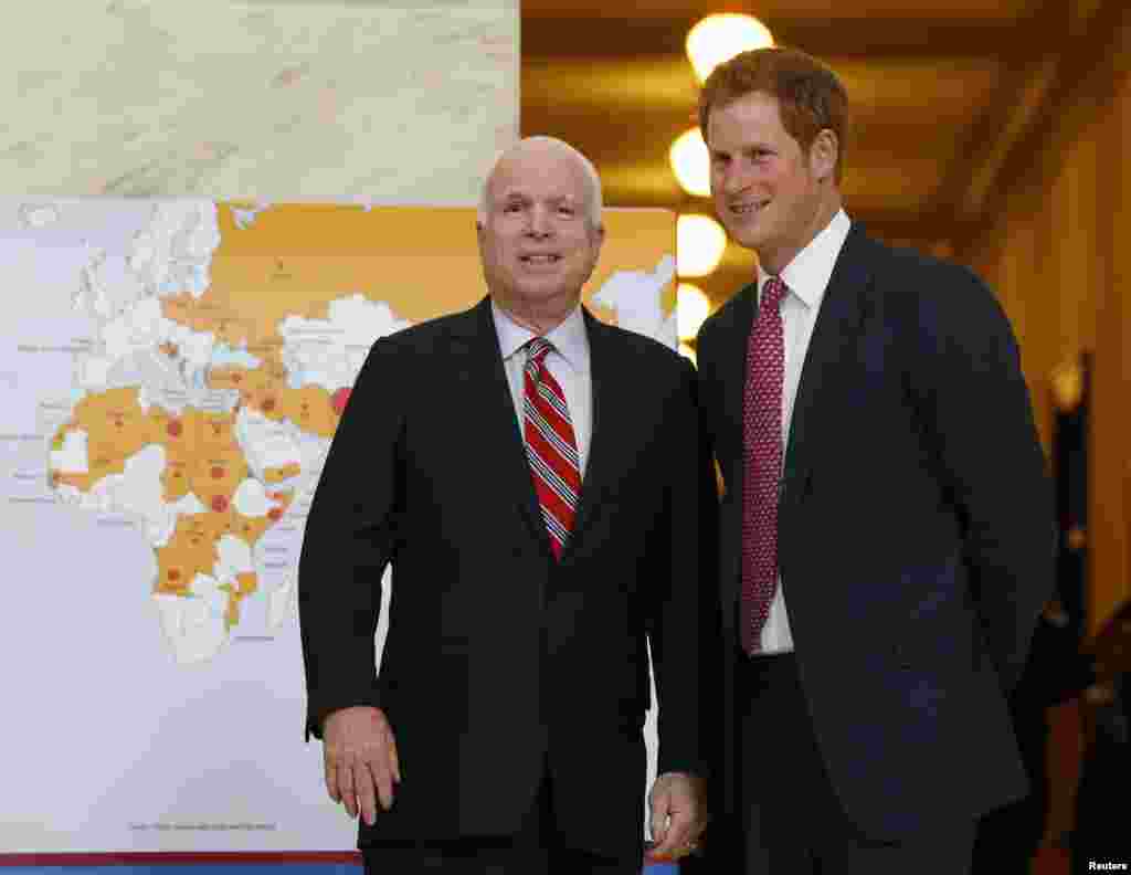 Britain's Prince Harry tours an exhibit on landmine removal by the organization Halo Trust, with U.S. Senator John McCain (R-AZ) in the Russell Building of the U.S. Capitol in Washington, May 9, 2013. Pictured alongside is a map of the world with red dots