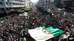 Algerians march with a giant national flag during a protest in Algiers, Algeria, March 15, 2019. Tens of thousands of people gathered Friday in Algeria's capital and other cities for what could be decisive protests against longtime leader Abdelaziz Bouteflika.