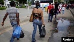 FILE - People cross to Venezuela over the Simon Bolivar bridge after shopping in Cucuta, Colombia, Dec. 1, 2016. Many Venezuelan women are selling their hair in Colombia in reaction to their country's struggling economy. 
