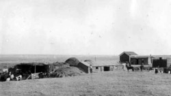 An 1889 photo of a sod home and farm built by settlers in Kansas