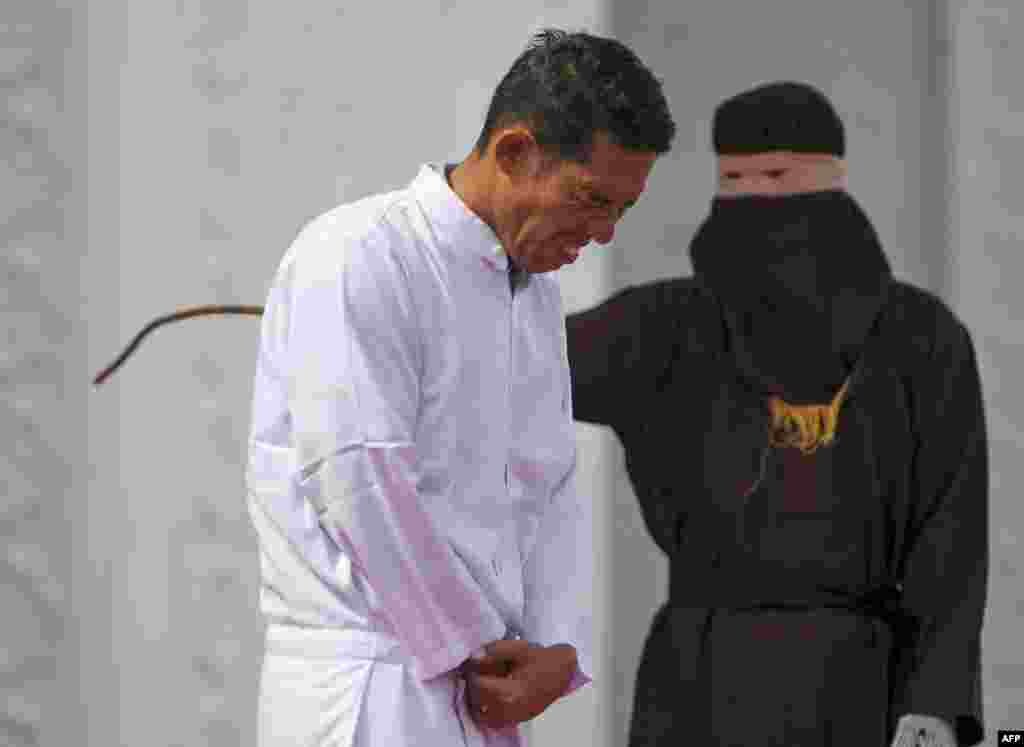 Jono Simbolon, an Indonesian Christian, grimaces in pain as he is flogged in front of a crowd outside a mosque in Banda Aceh, Aceh province. Simbolon was publicly flogged on January 19 for selling alcohol in conservative Aceh province.