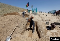 FILE - Afghan men dig graves for the victims of Sunday's suicide attack in Kabul, Afghanistan, April 23, 2018.