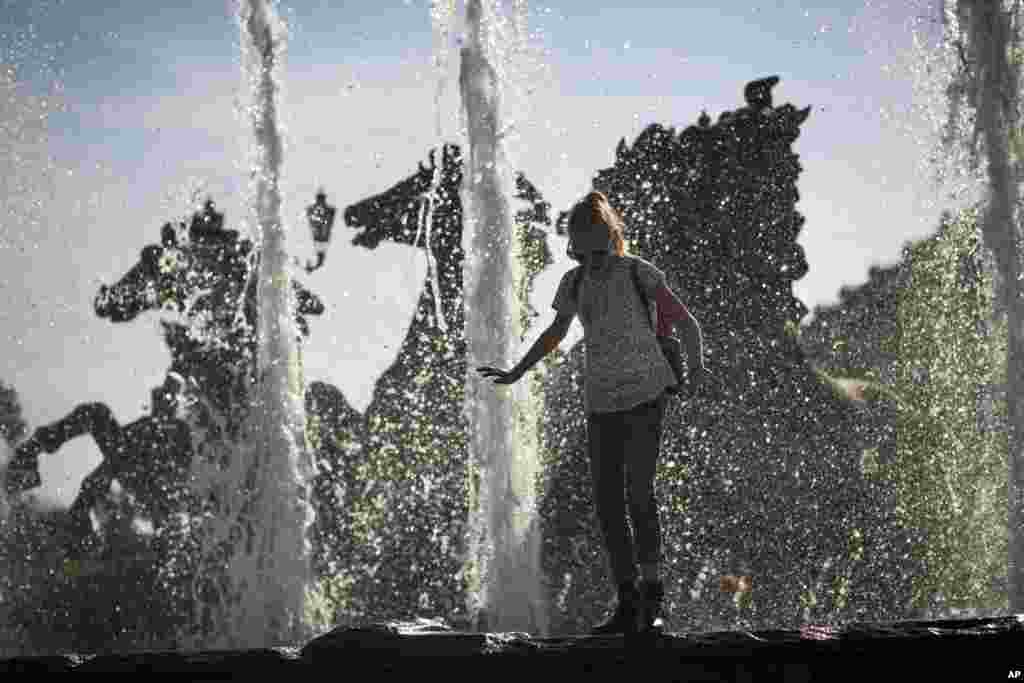 A girl cools herself at a fountain at Alexander Garden near the Kremlin Wall in Moscow, Russia.&nbsp; Moscow residents who were disappointed by a largely cool and rainy summer have been relishing this week&#39;s sunshine and temperatures reaching nearly 30 degrees (85 F).