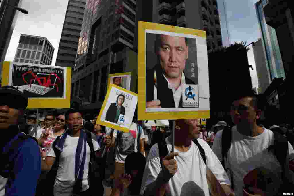 Para demonstran membawa potret-potret pengacara HAM China, Pu Zhiqiang (kanan) dan jurnalis Gao Yu, dalam protes yang diikuti puluhan ribu orang untuk menuntut demokrasi yang lebih besar di Hong Kong (1/7). (Reuters/Bobby Yip)
