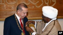 FILE - Sudan's President Omar al-Bashir, right, presents Turkey's President Recep Tayyip Erdogan with his country's highest medal during a ceremony in Khartoum, Sudan, Sunday, Dec. 24, 2017. Erdogan is in Sudan for a two-day State visit.