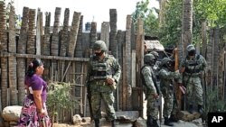 Mexican army soldiers stand outside a home where gunmen killed an elderly woman and two of her grandchildren in the Pacific resort city of Acapulco, March 15, 2011