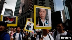 Demonstran membawa foto aktivis HAM, Pu Zhiqiang (Kanan) dan wartawati Gao Yu dalam sebuah protes di Hong Kong 1/7/2014.