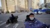 Mensajeros hacen su trabajo con máscaras protectoras en un desolado distrito comercial de Beijing, China, el 18 de febrero de 2020.