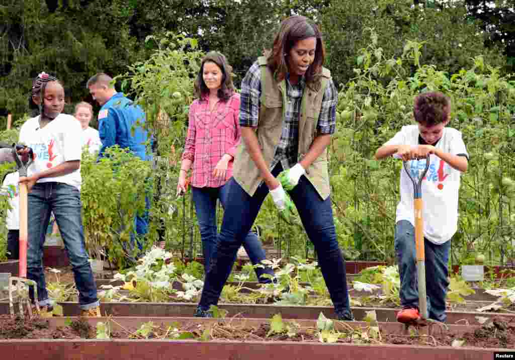 Ibu negara Michelle Obama memberi semangat pada seorang siswa sekolah yang sedang ikut memanen sayuran di kebun dapur Gedung Putih (6/10). (Reuters/Mike Theiler)