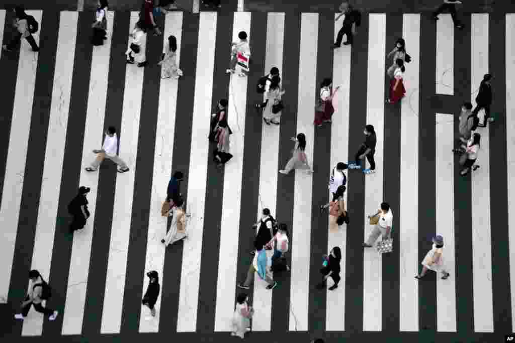 People wearing protective masks to help curb the spread of the coronavirus walk along a pedestrian crossing in Tokyo, Japan.