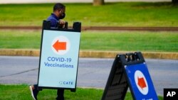 FILE - A worker posts placard for a COVID-19 vaccination clinic at the Reading Area Community College in Reading, Pa, Sept. 14, 2021. 