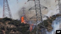 Smoke from wildfires rises from a hillside near power lines outside Azusa, Calif., Monday, June 20, 2016. New wildfires erupted Monday in Southern California and chased people from their homes as an intensifying heat wave stretching from the West Coast to New Mexico blistered the region.