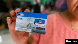 A woman holds up a SIM card, which she won in a June lottery, in Rangoon, Burma, June 24, 2013. 
