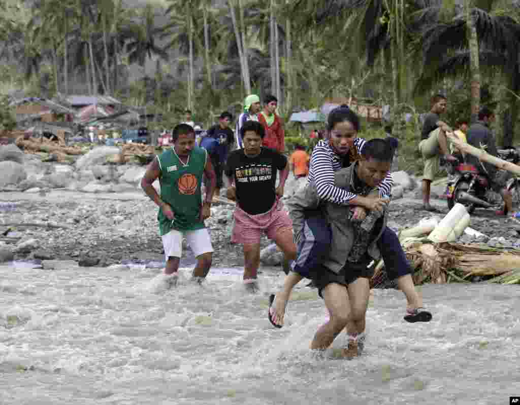 菲律宾南部孔波斯特拉省新巴丹镇的安达普村发生山洪暴发后，灾区村民设法过河
