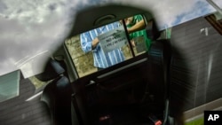 FILE - Drivers place a sign at the window of a taxi that demands compliance to the law for taxi service during a protest against the services of private companies, in Pamplona, northern Spain, May 30, 2017. 