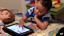 FILE - Frankie Thevenot, 3, plays with an iPad in his bedroom at his home in Metairie, La. 