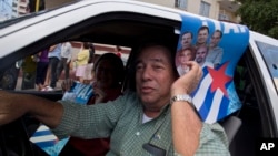 A man drives his car holding a poster with pictures of the Cuban Five, celebrating their freedom, in Havana, Cuba, Dec. 17, 2014. 