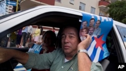 A man drives his car holding a poster with pictures of the Cuban Five, celebrating their freedom, in Havana, Cuba, Wednesday, Dec. 17, 2014. After a half-century of Cold War acrimony, the United States and Cuba abruptly moved on Wednesday to restore diplo