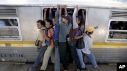 Indonesian men struggle to board a packed commuter train at a station in Jakarta, May 11, 2010.