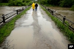 Robert Collins, left, and Bobby Joe Branston watch rising waters in the Fishing River from a condemned bridge in Mosby, Missouri, May 21, 2019.