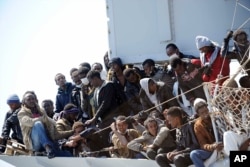 FILE - Migrants wait to disembark from the Italian Navy vessel "Chimera" in the harbor of Salerno, Italy, April 22, 2015.