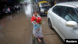 Seorang bocah laki-laki menjual bunga mawar di tengah jalan dalam hujan di Mumbai (12/7). (Reuters/Danish Siddiqui) 