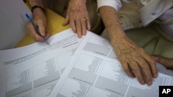 Para pemilih memeriksa kartu suara sebelum memberikan suara dalam pemilu parlemen pada sebuah TPS di ibukota Zagreb Minggu (11/9).