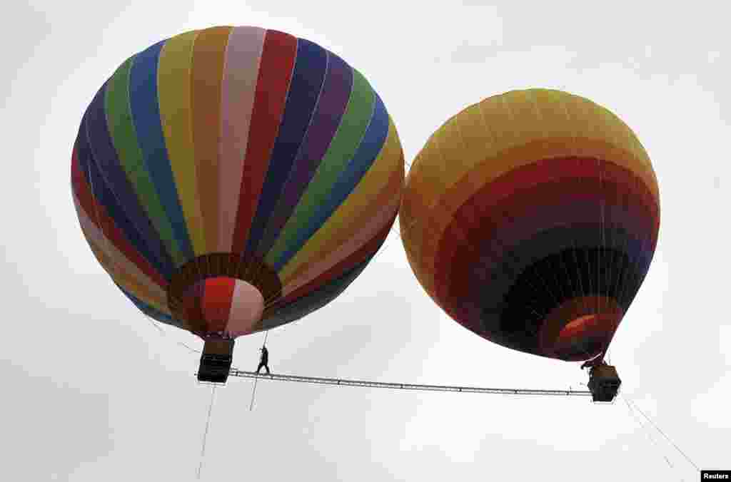 Aisikaier Wubulikasimu, 40-year-old Uighur acrobat, walks on a 18m long (59 ft), 50 mm wide (2 inch) tightrope strung between two hot air balloons, in Shilin county, Yunnan province, China, July 30, 2013. Wubulikasimu has previous broken two Guinness World Record for the fastest tightrope walk over 100m in 2009 and the steepest tightrope walk in 2011.