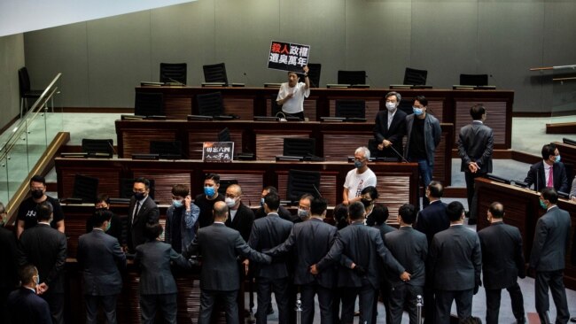 在香港的一次立法会会议上，亲民主议员(上)在一场关于禁止侮辱中国国歌的法律的辩论中被保安（下）阻挡。(2020年6月4日)
