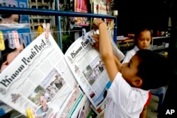 FILE - A boy hangs up copies of the English-language Phnom Penh Post at a newsstand in Phnom Penh, Cambodia, Jan. 8, 2008.