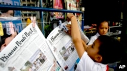 FILE - A boy hangs up copies of the English-language Phnom Penh Post at a newsstand in Phnom Penh, Cambodia, Jan. 8, 2008.