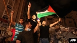 Sejumlah warga Palestina melambaikan bendera saat merayakan gencatan senjata antara Israel dan dua kelompok bersenjata Palestina di Kota Gaza, yang dimediasi oleh Mesir, Jumat, 21 Mei 2021. (Foto: AFP)