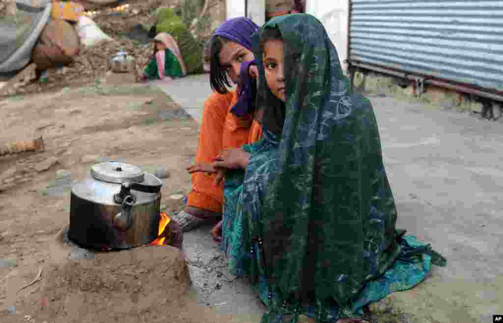 Internally displaced girls warm up by a stove in the Achin district of Afghanistan.