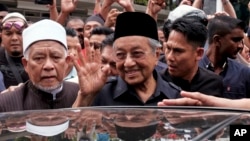 Malaysian Prime Minister Mahathir Mohamad, center, waves to crowds leaving National Mosque after performing Friday prayers in Kuala Lumpur, Malaysia, Friday, May 11, 2018.