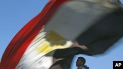 A man carries an Egyptian flag near Cairo's Tahrir Square where demonstrators are gathering to mark the first anniversary of Egypt's uprising, January 25, 2012.