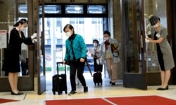 FILE - Staff members wearing protective masks and face shields greet customers as the Nihombashi Takashimaya Shopping Center partially reopens to customers, amid the coronavirus disease (COVID-19) outbreak in Tokyo, Japan, May 18, 2020. (REUTERS)