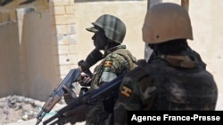 FILE - Ugandan soldiers patrol a street in the southern town of Merka, 90 km north of Somalia's capital Mogadishu, July 17, 2016, as part of the African Union Mission in Somalia (AMISOM).