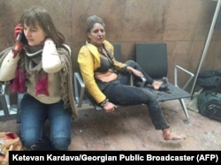 An injured woman looks on as another speaks on her mobile phone following twin blasts at Brussels airport in Zaventem on March 22, 2016.