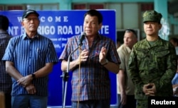 FILE - Philippines President Rodrigo Duterte (C), flanked by military and civilian officials, talks after visiting soldiers, wounded in battles with Maute rebels, at a military camp in Cagayan De Oro, southern Philippines, June 11, 2017.