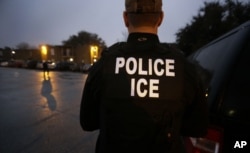 FILE - U.S. Immigration and Customs Enforcement (ICE) agents enter an apartment complex looking for a specific undocumented immigrant convicted of a felony during an early morning operation in Dallas, Texas, March 6, 2015.
