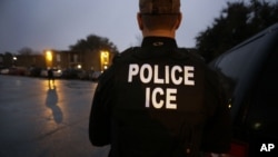 Para petugas Penegak Bea Cukai dan Imigrasi AS memasuki kompleks apartemen untuk mencari imigran gelap yang divonis karena melakukan kejahatan dalam operasi dini hari di Dallas, Texas, 6 Maret 2015.