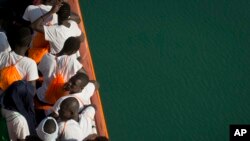 FILE - African migrants who were rescued from the Mediterranean Sea north of the Libyan coast, stand on the deck as the boat approaches the port of Pozzallo in Sicily, Italy, Sept. 1, 2017. 