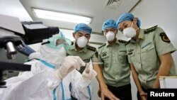 2014年8月11日，中国一位卫生检疫人员（左）在青岛机场化验室里向海关警察介绍埃博拉病症特点。（资料照片）