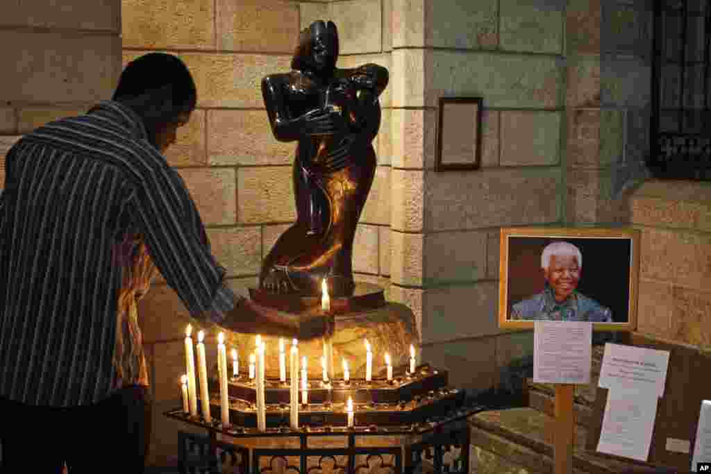 Un hombre coloca una vela pidiendo por la salud de Nelson Mandela el día de su cumpleaños en la Catedral St. George de Ciudad del Cabo. 